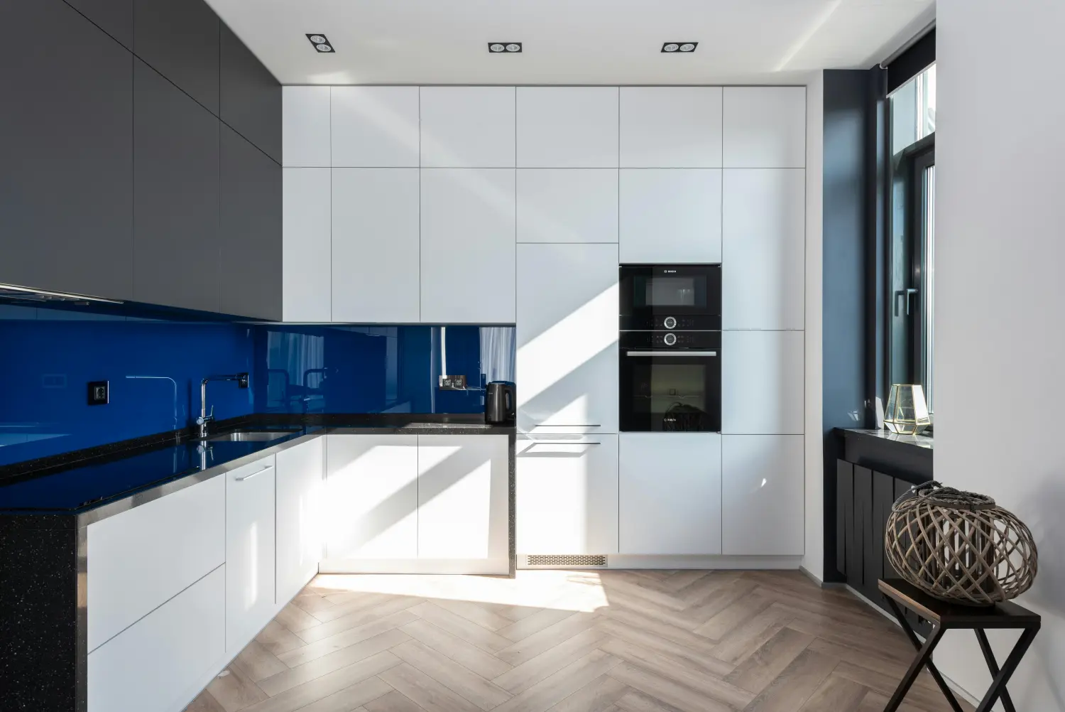 Moderne weiße Küche mit einer fugenlosen Küchenrückwand aus blauem Glas