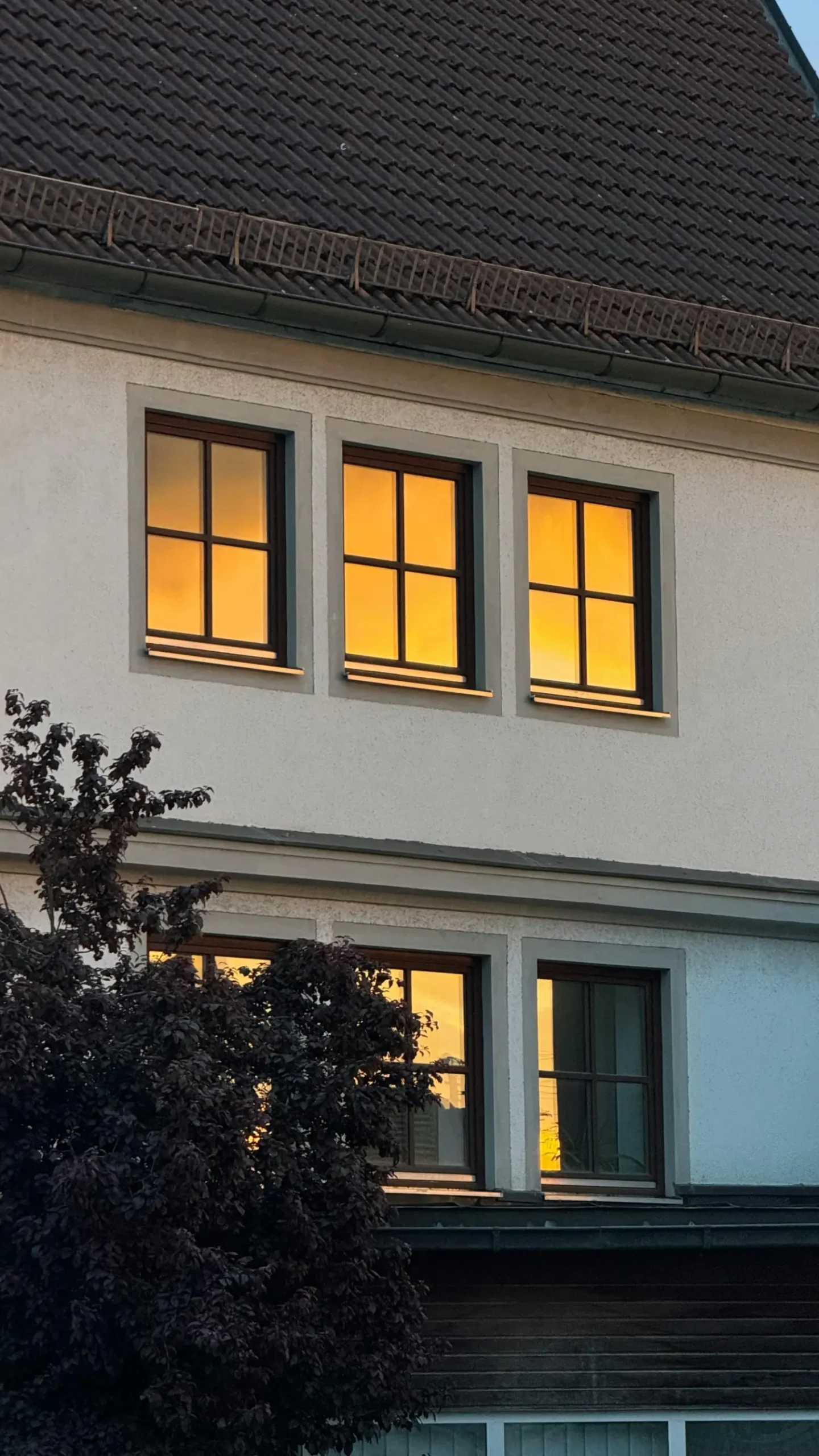 Einfamilienhaus mit beleuchteten Fenstern bei Dämmerung, Symbol für Einbruchschutz.