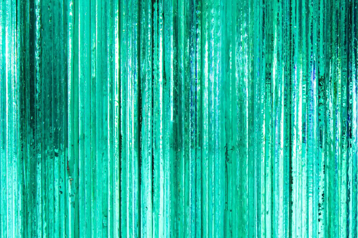 Nahaufnahme von geschichteten Dünnglasplatten mit türkis-grüner Lichtbrechung